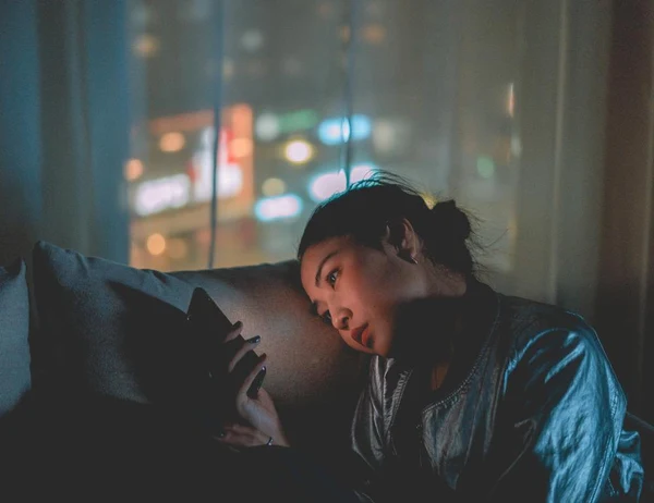 A woman endlessly scrolls on her social media apps on her phone at night