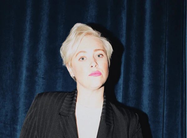 A photo of Caroline King, COO of Lather, posing in front of blue curtains