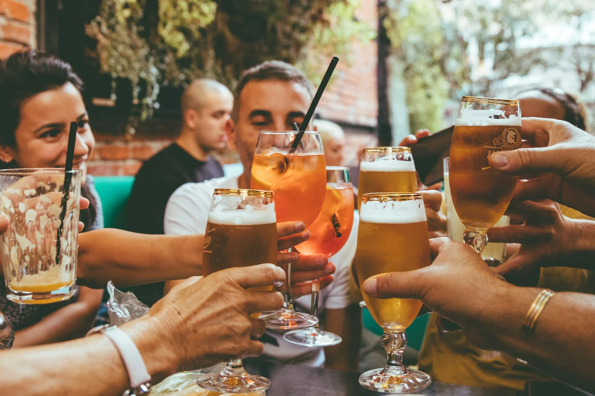 A group of friends cheers their beers and alcoholic drinks in a bar