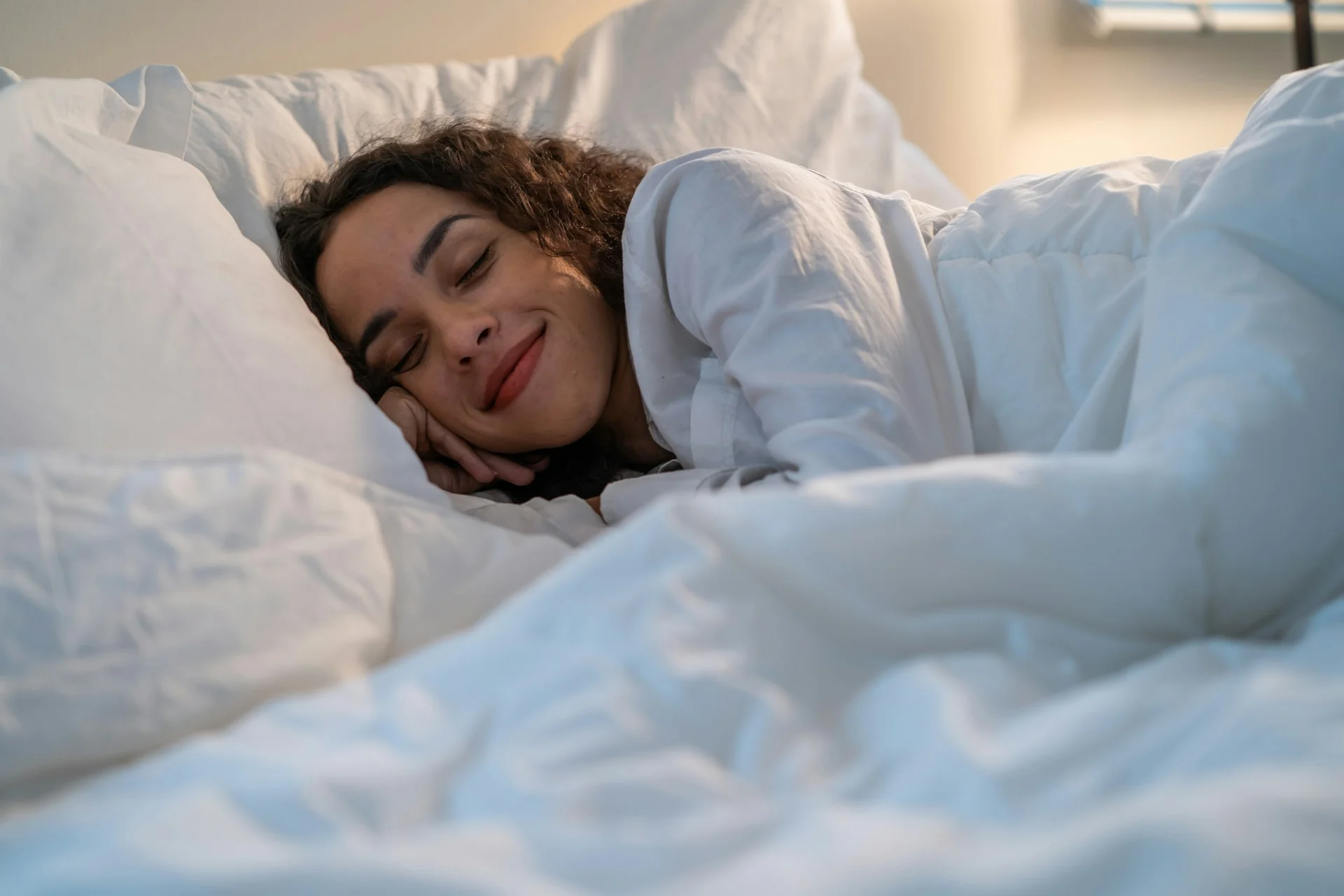A woman sleeps comfortably in her bed, wrapped in sheets, after taking CBD