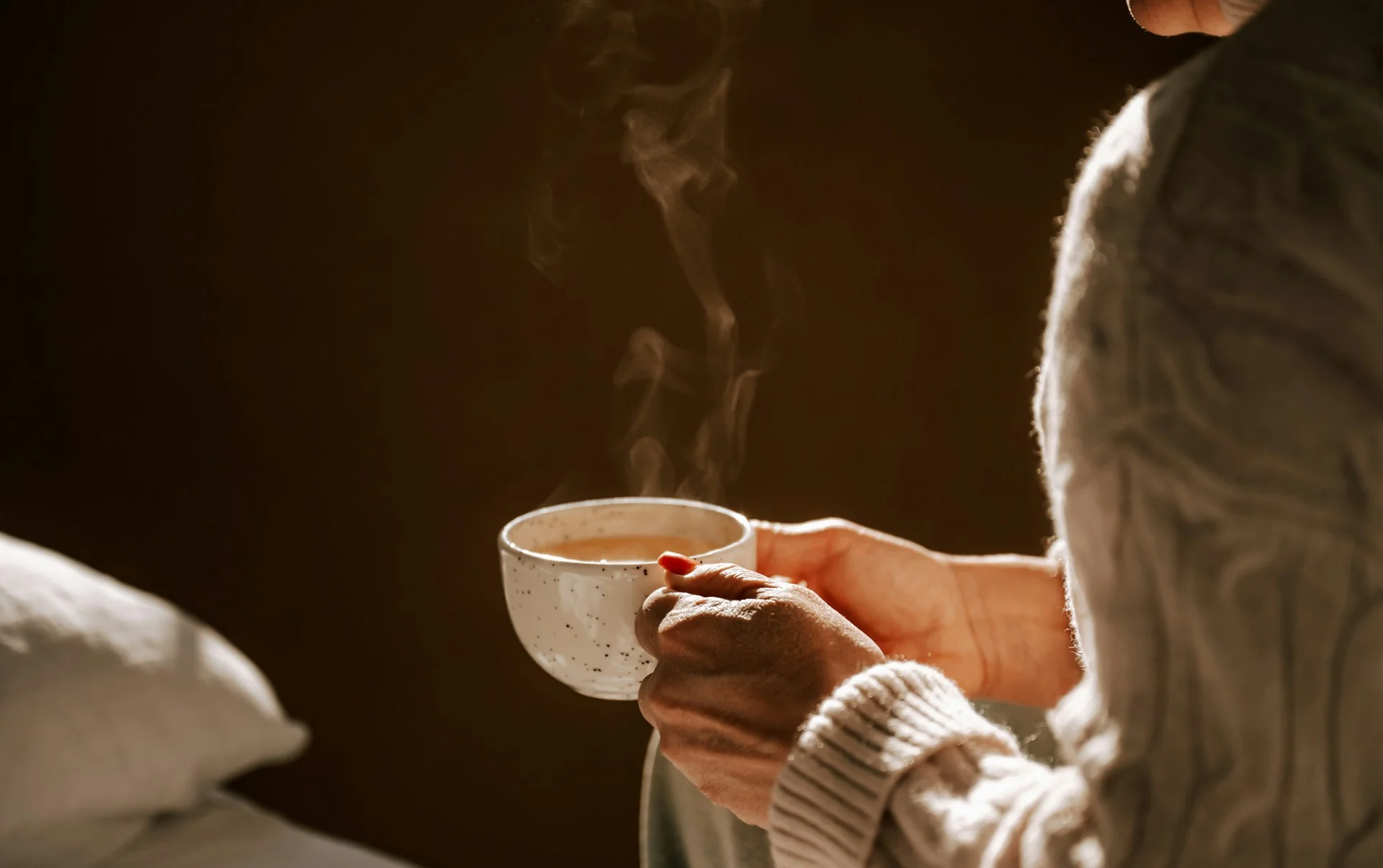 A woman softly holding a steaming cup of kava tea, enjoying the experience