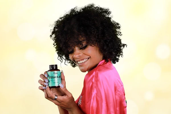 A woman holds up a bottle of vegan CBD gummies as a self-care practice for dealing with the Post-concert blues