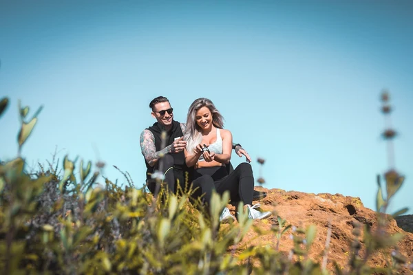 A relaxed and happy couple sit on a mountain top after a hike