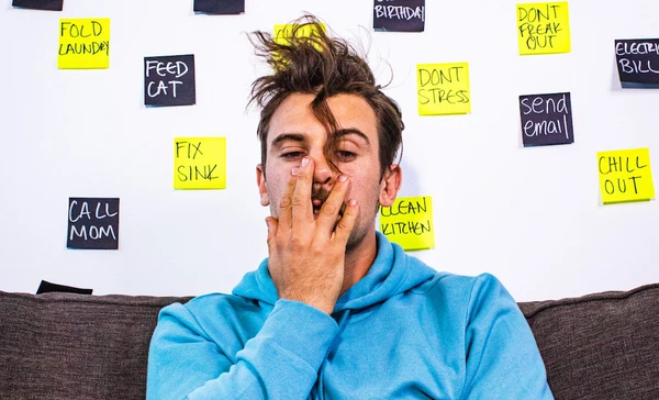 A man grabs his face because he is stressed, exhausted and falling asleep at work