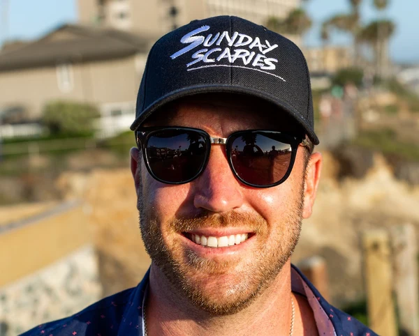 A photo of Mike Sill, CEO & Co-founder of Sunday Scaries, wearing a Sunday Scaries hat and sunglasses