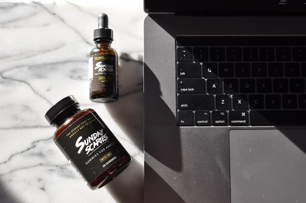 The Sunday Scaries Sidepiece bundle is placed next to a MacBook Pro