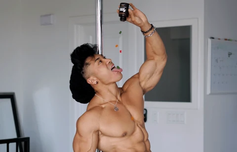 A shirtless, muscular man pours a bottle on Sunday Scaries CBD gummies into his mouth