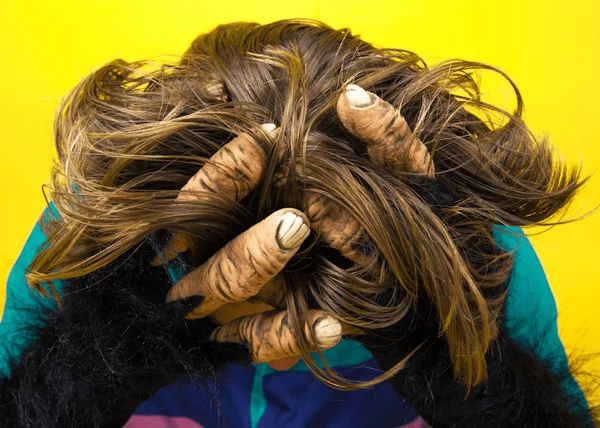 A stressed out man is holding his head in his hands, and he has monster hands