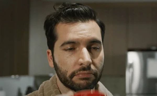 Man is overworked and looks sluggish in his kitchen drinking coffee