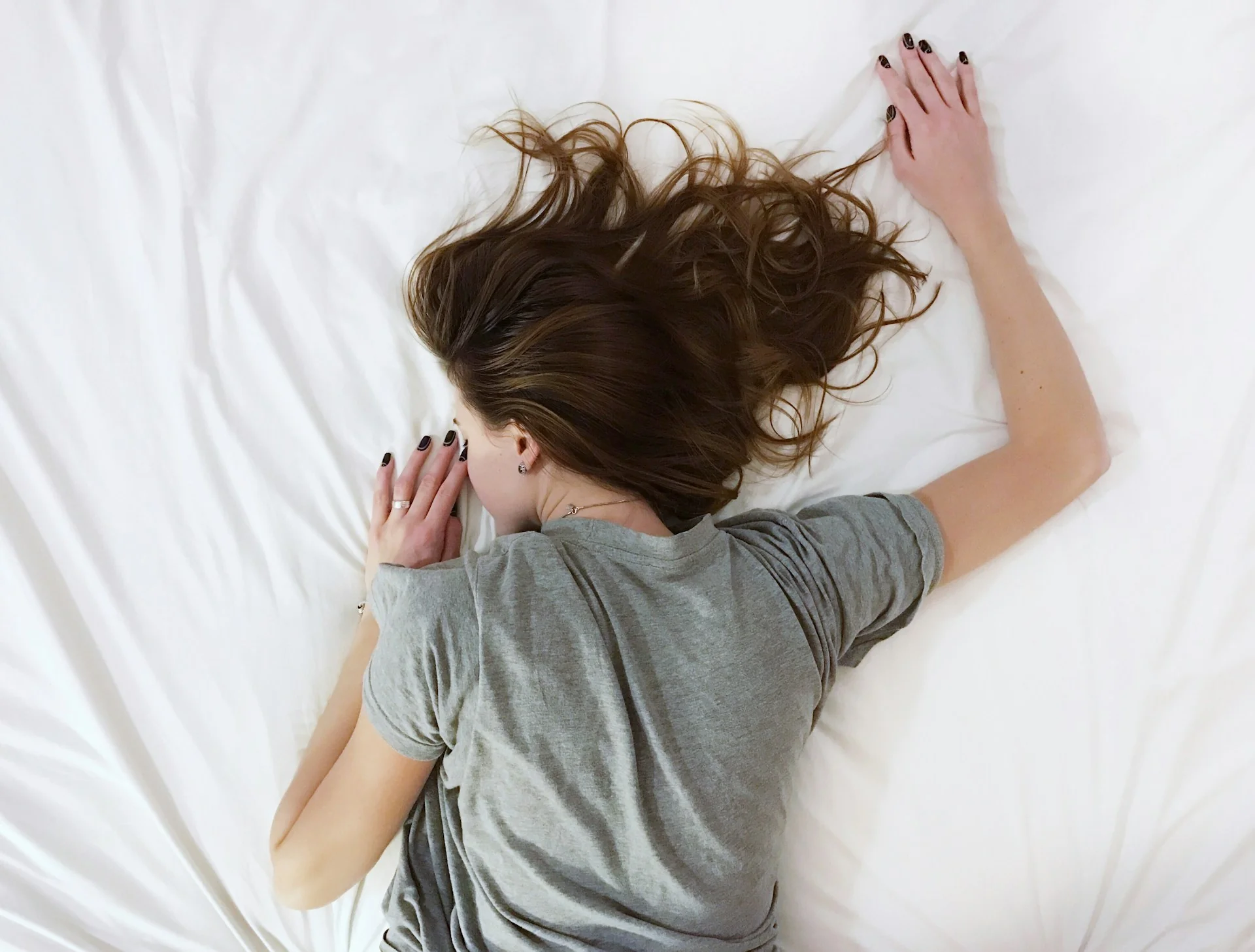 A top-down view of a girl sleeping, sprawled out across her bed