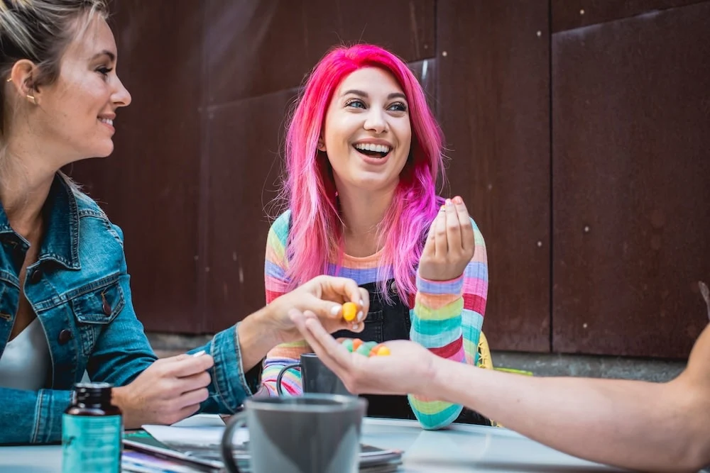 A woman holds up a THC gummy and explains to her friends how Delta-9 gummies are safe