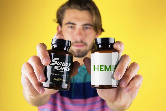 A man holds up two bottles showing hemp gummies vs. CBD gummies and what the difference is