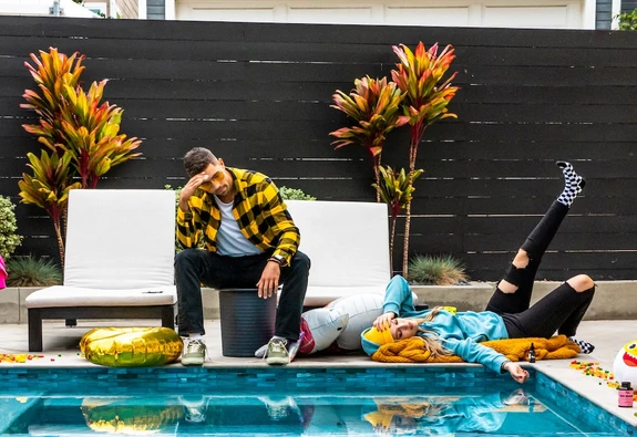 A man and woman are hungover by the pool