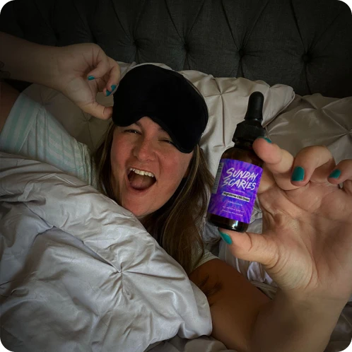 A woman with an eyemask on her forehead takes Sunday Scaries CBN + CBD sleep oil to shut her mind down before bed