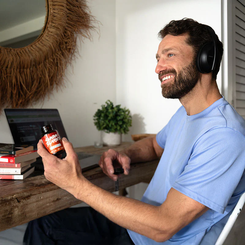 A man with headphones on hold mushroom gummies to increase his performance at work