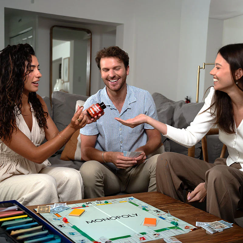 Three friends eat nootropics gummies while playing monopoly